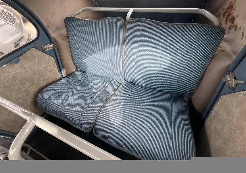 Vue intérieure du siège arrière rayé bleu clair de la Citroën 2 CV de 1960 avec structure métallique blanche visible.
