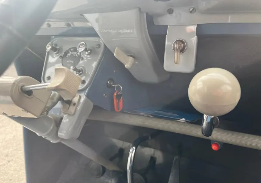 Vue rapprochée de l’intérieur bleu clair d’une Citroën 2 CV 1960, montrant le tableau de bord et levier de vitesses blanc.