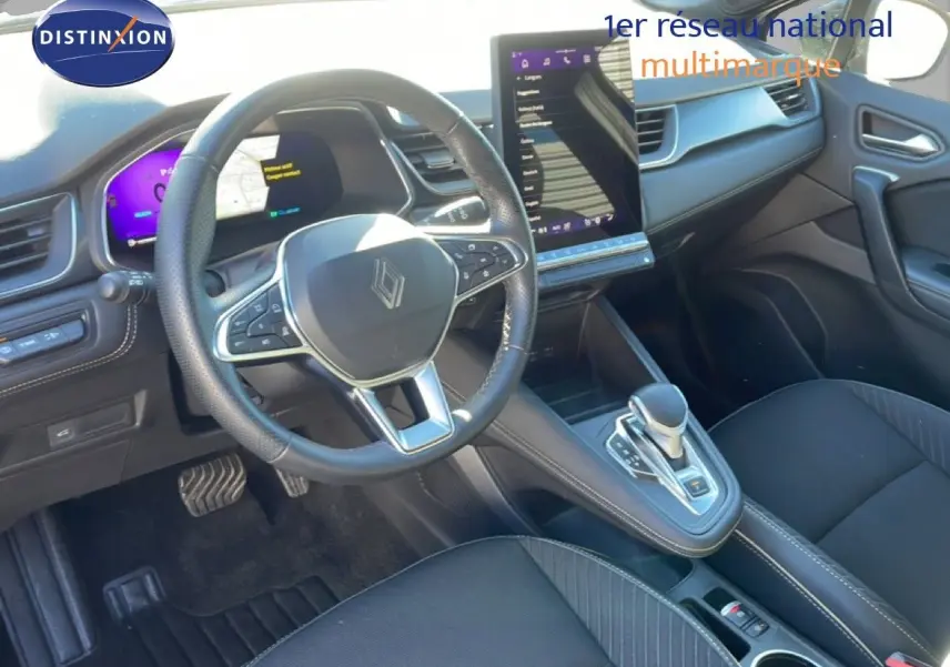 Vue intérieure centrée sur le volant et la console centrale du Renault Symbioz 2025, finition Iconic, sièges noirs et écran tactile vertical.