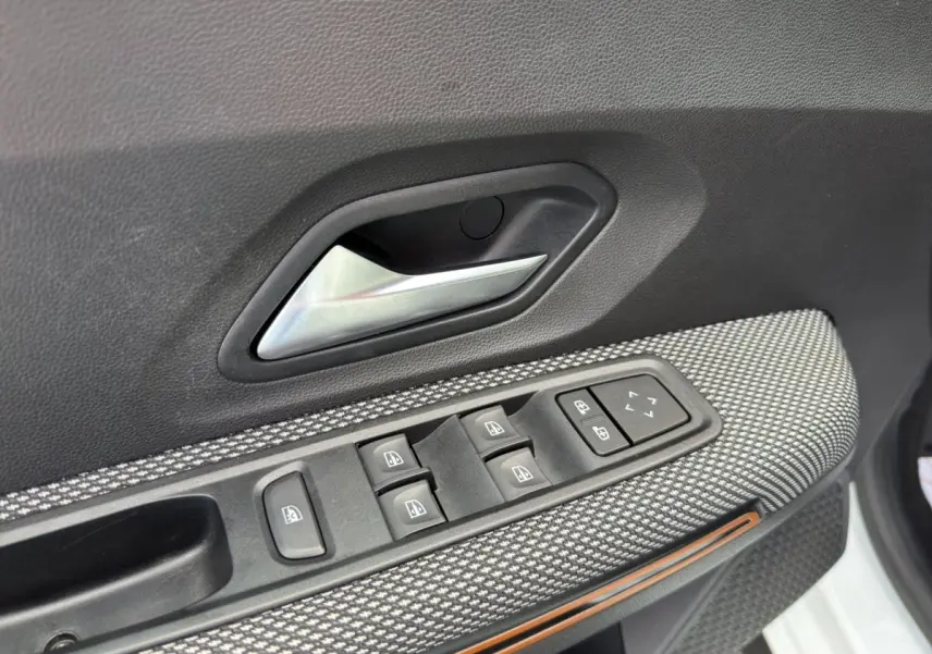 Détail de la porte côté conducteur de la Dacia Sandero Stepway blanche, avec commandes des vitres et poignée intérieure.
