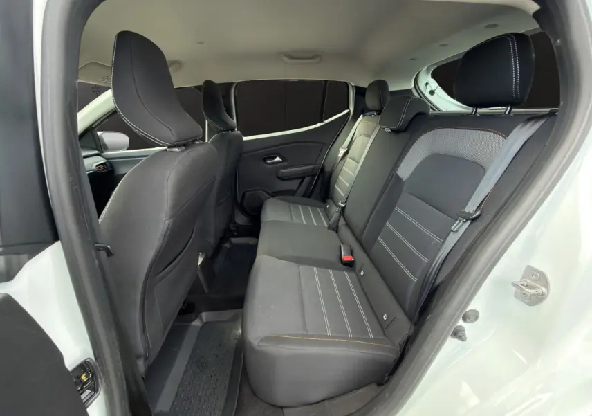 Vue intérieure arrière de la Dacia Sandero Stepway blanche, montrant la banquette noire avec surpiqûres contrastantes.