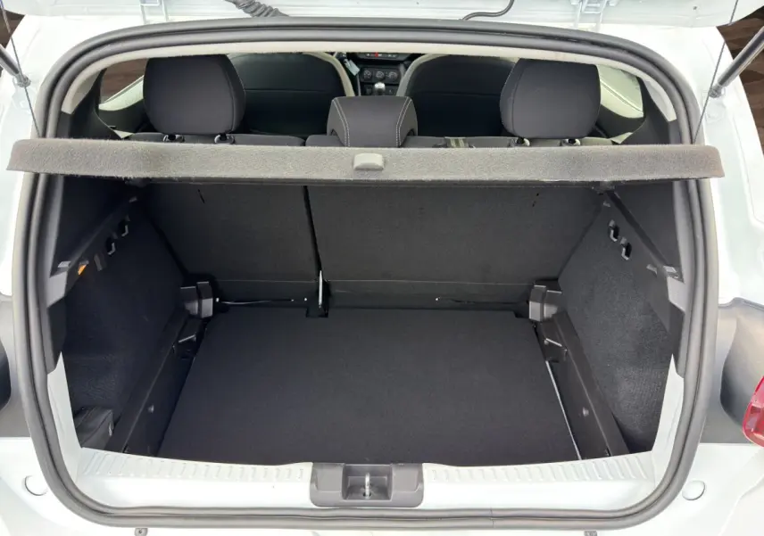 Vue du coffre ouvert d'une Dacia Sandero Stepway blanche, montrant l'espace de chargement et la banquette arrière noire.