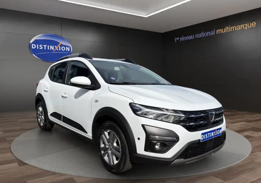 Dacia Sandero Stepway blanc vue 3/4 avant droit avec barres de toit et détails noirs contrastants.