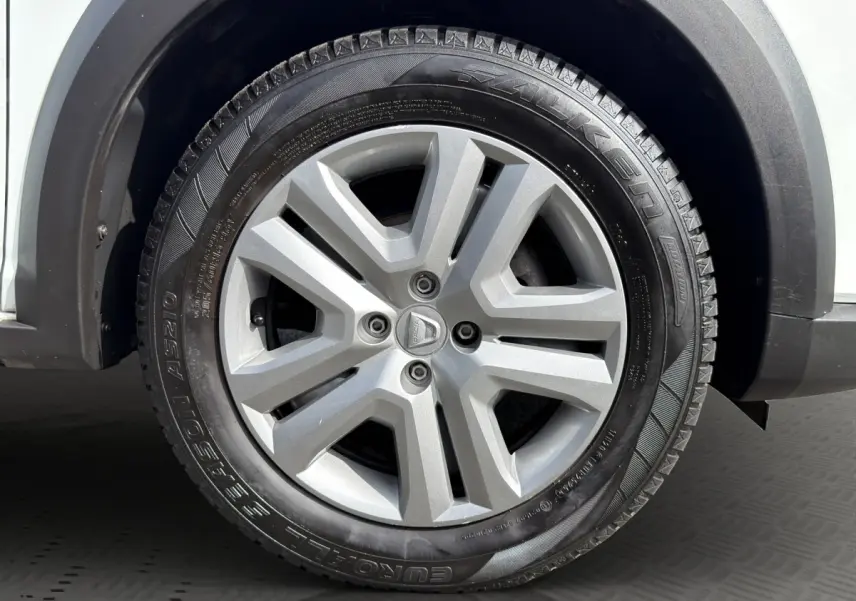 Gros plan sur la roue avant droite d'une Dacia Sandero Stepway blanche, avec jante alliage grise et pneu Falken.