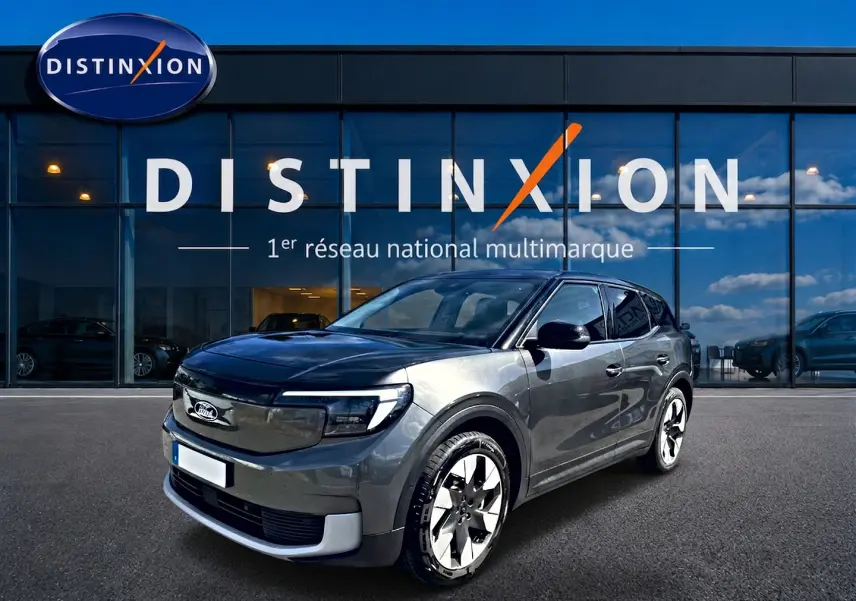Ford Explorer électrique gris en vue 3/4 avant droit devant une vitrine avec logo Distinxion.