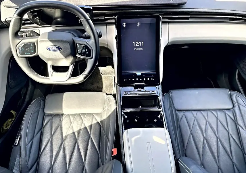 Vue intérieure de face du Ford Explorer 2025 gris, montrant le volant multifonction et l'écran tactile central vertical.