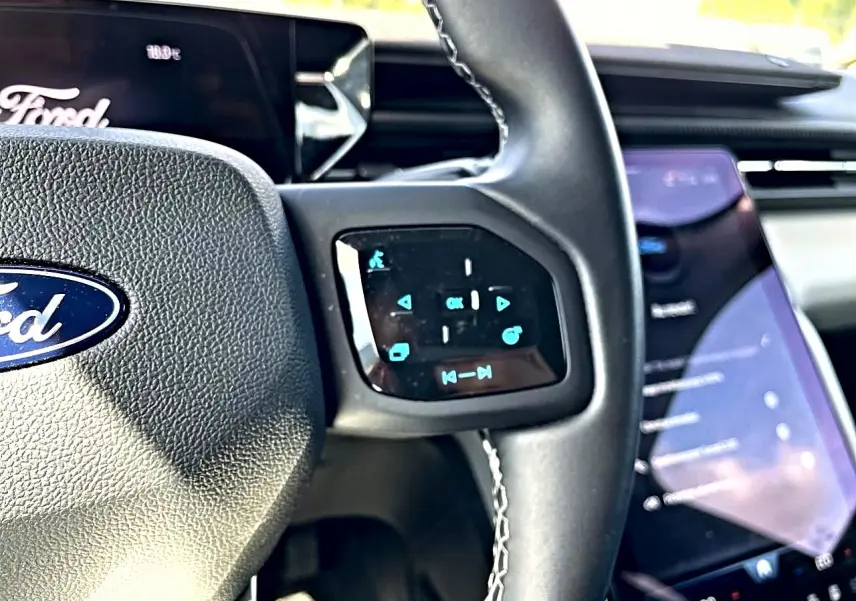 Gros plan sur le volant multifonction noir et l’écran tactile vertical du tableau de bord du Ford Explorer gris.