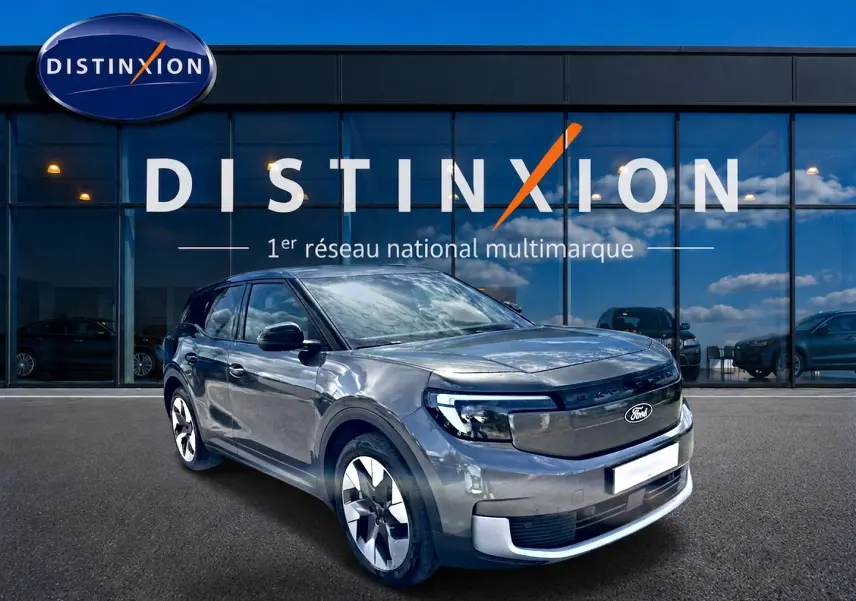 Ford Explorer électrique gris métallisé vu en 3/4 avant droit devant une vitrine avec logo Distinxion.