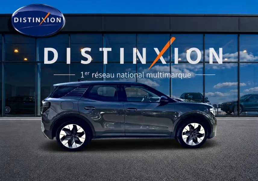 Vue de profil côté gauche d'un Ford Explorer gris électrique 2025, avec jantes alu distinctives, devant une vitrine Distinxion.