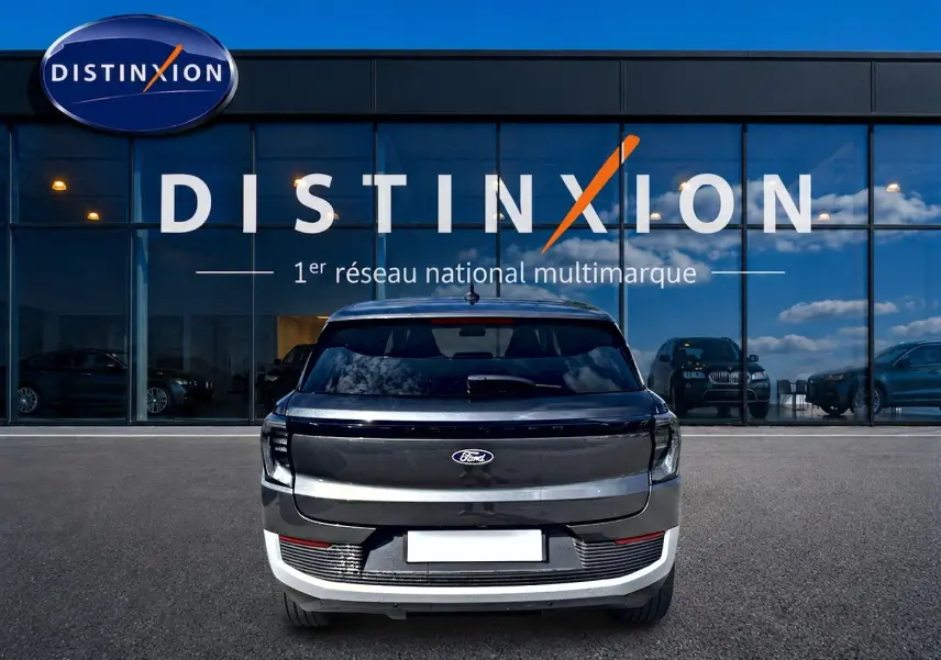 Vue arrière d'un Ford Explorer gris électrique 2025 garé devant une vitrine avec logo Distinxion.