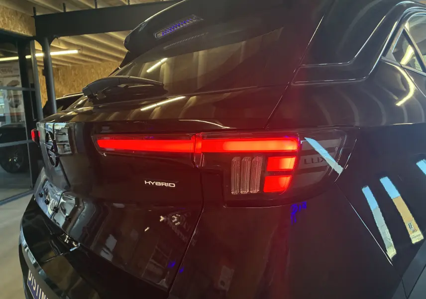 Vue arrière droite d'un Opel Mokka noir 2025 avec feux LED allumés et badge Hybrid visible sur le hayon.