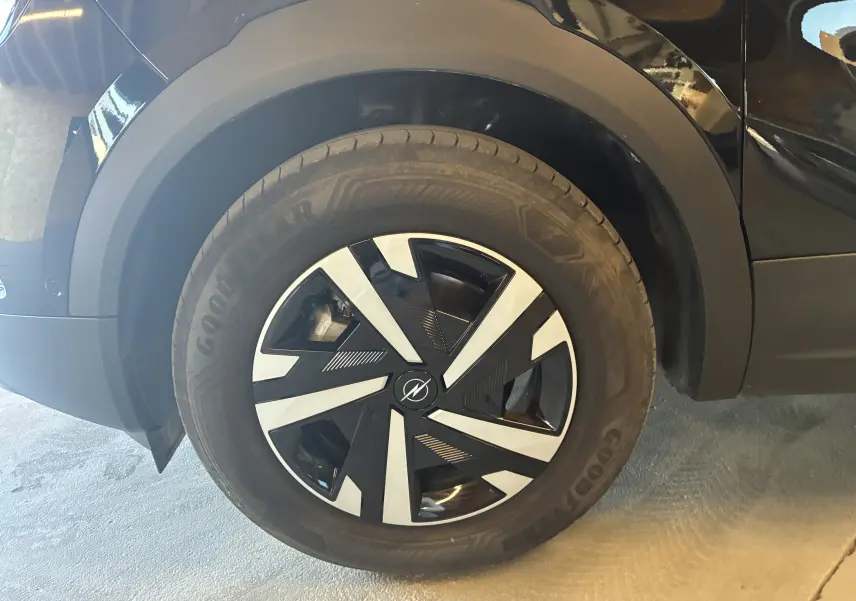 Gros plan sur la roue avant gauche noire d’un Opel Mokka 1.2 Turbo Hybrid 2025 avec jante au design géométrique bicolore.