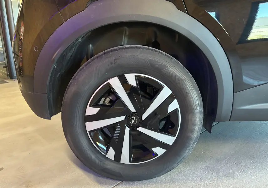 Gros plan sur la roue avant gauche noire de l’Opel Mokka 1.2 Turbo Hybrid 136 Edition avec jante bicolore distinctive.