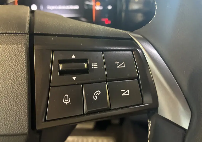 Gros plan sur les commandes de volume et téléphone au volant du Opel Mokka noir 2025, version hybride.