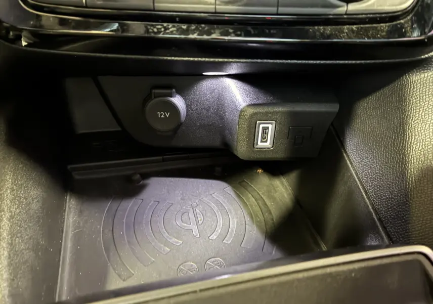 Détail intérieur montrant une prise 12V, un port USB-C et un espace de recharge sans fil dans l’Opel Mokka noir 2025.