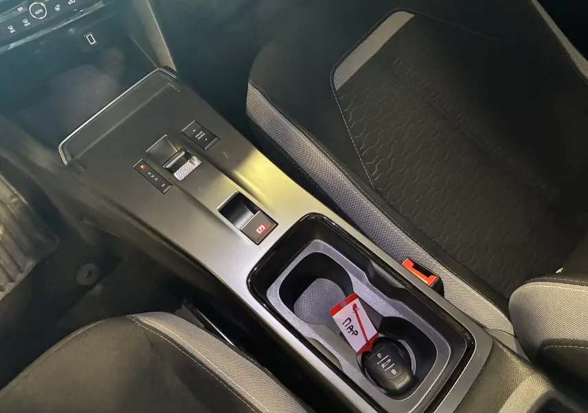 Vue intérieure de la console centrale noire de l’Opel Mokka 2025 avec boîte auto et clé dans le porte-gobelets.