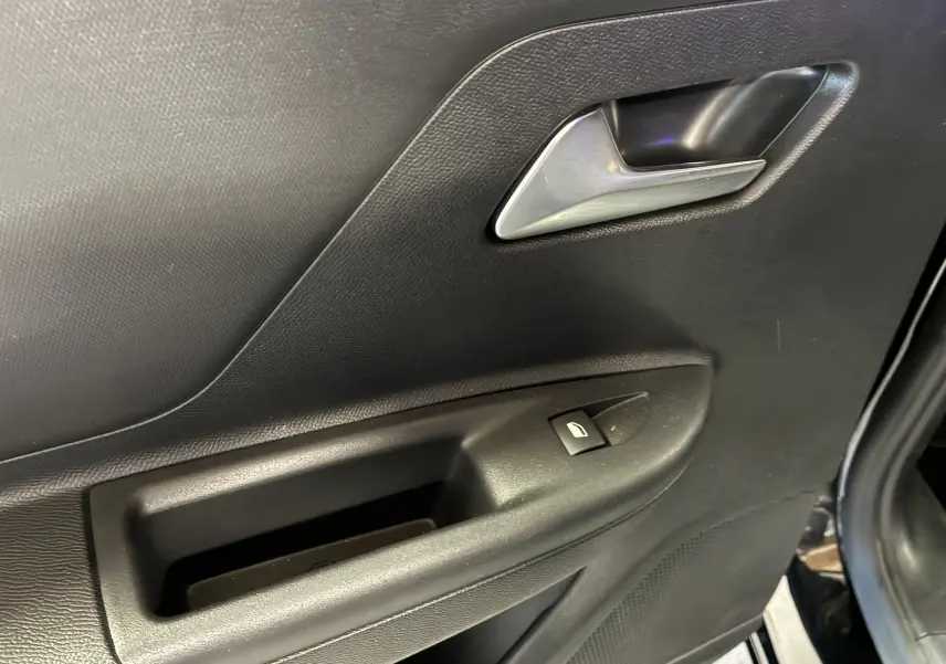 Détail de la porte intérieure côté droit de l'Opel Mokka 2025 noire, avec poignée argentée et bouton de lève-vitre.