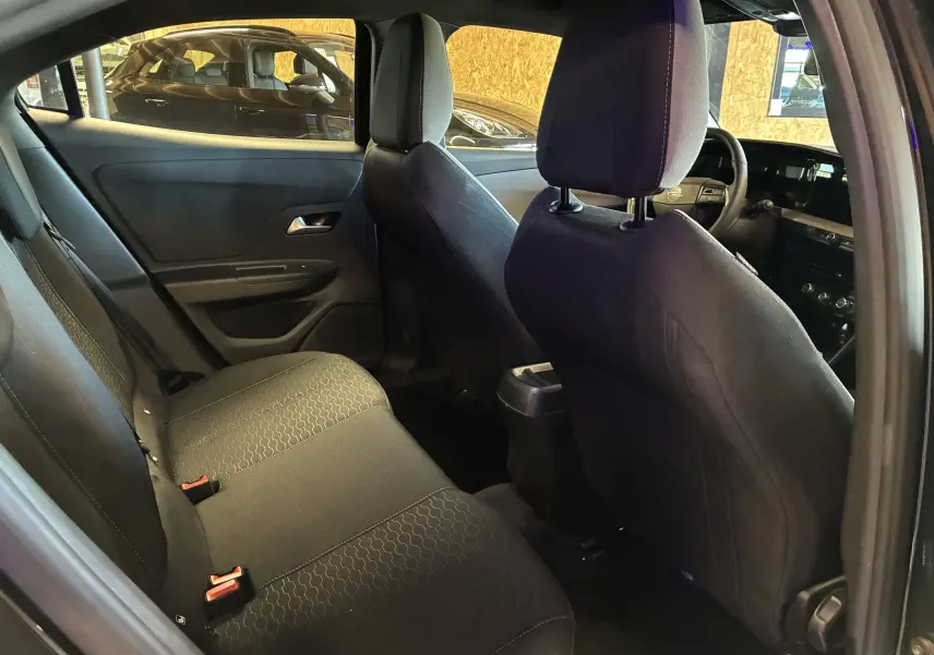 Vue intérieure arrière gauche de l’Opel Mokka 2025 noire, montrant les sièges arrière et le tableau de bord à l’avant.