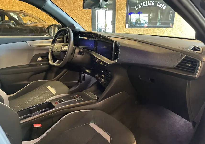 Intérieur avant droit de l’Opel Mokka noir 2025, tableau de bord moderne avec écran tactile et sièges tissu bicolores.