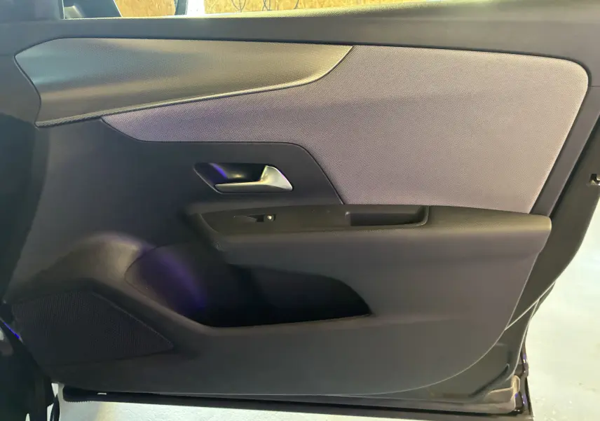 Intérieur de la porte côté gauche de l’Opel Mokka 2025 noir, avec poignée argentée et habillage tissu gris.