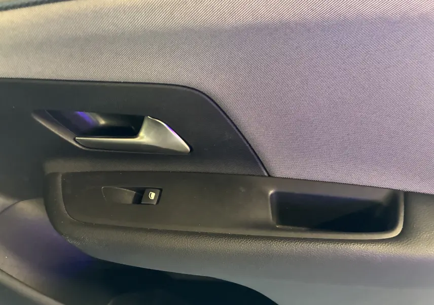 Gros plan sur la poignée intérieure et le bouton de lève-vitre côté gauche de la porte d’une Opel Mokka noire hybride 2025.