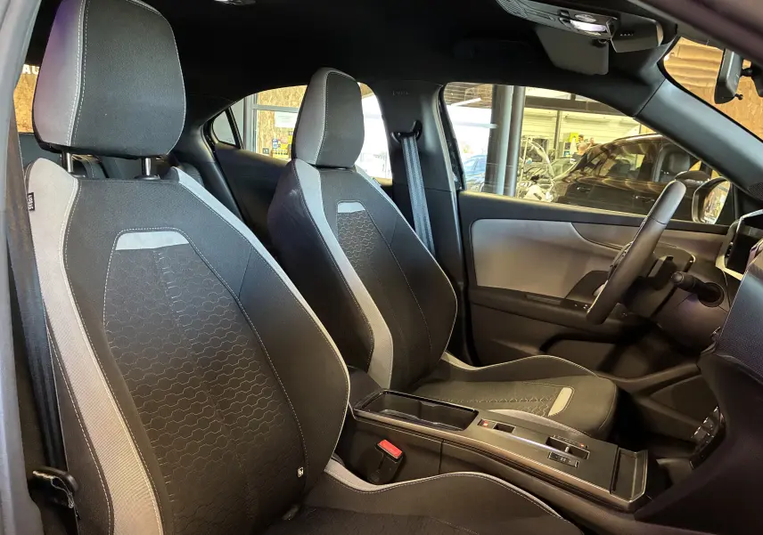 Vue intérieure de profil droit montrant les sièges avant noirs et gris de l’Opel Mokka 2025 hybride avec console centrale moderne.