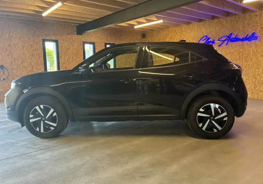 Opel Mokka 2025 noir vue de profil côté gauche, avec jantes noires et détails modernes en intérieur bois.