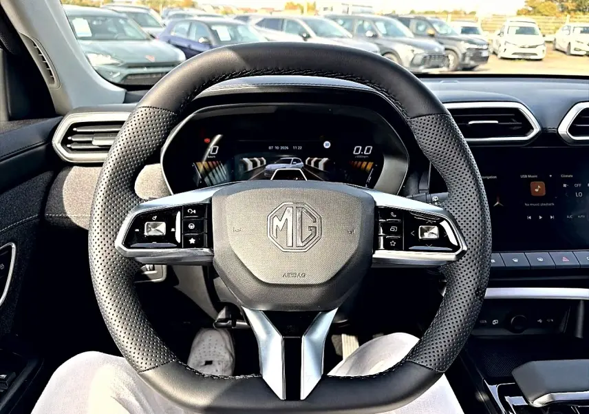 Vue intérieure centrée sur le volant noir perforé du MG ZS 1.5 hybrid 2026 avec tableau de bord numérique et écran tactile.