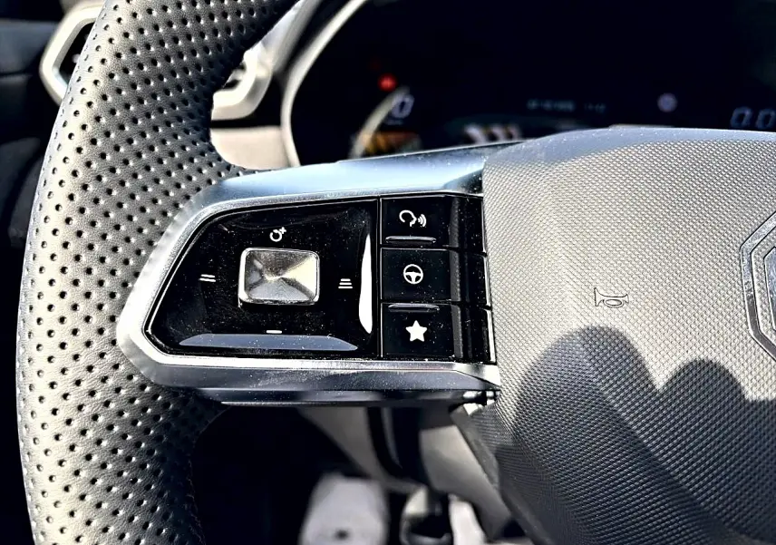 Gros plan sur les commandes gauche du volant perforé du MG MOTOR ZS 1.5 hybrid 197 Cosmic Silver 2026.