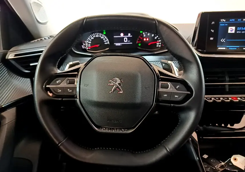 Vue rapprochée du volant cuir noir de la Peugeot 2008 2022 avec tableau de bord numérique et écran tactile central.