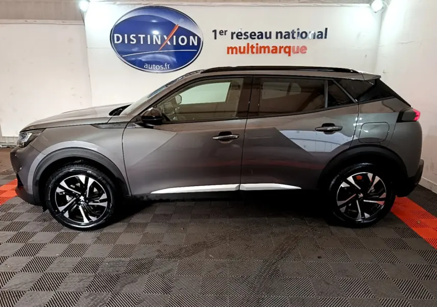 Profil côté gauche du Peugeot 2008 gris foncé 2022 dans un showroom avec jantes noires et détails chromés.