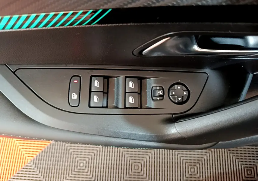 Panneau de commandes des vitres et rétroviseurs côté conducteur du Peugeot 2008 gris foncé, avec poignée de porte noire.