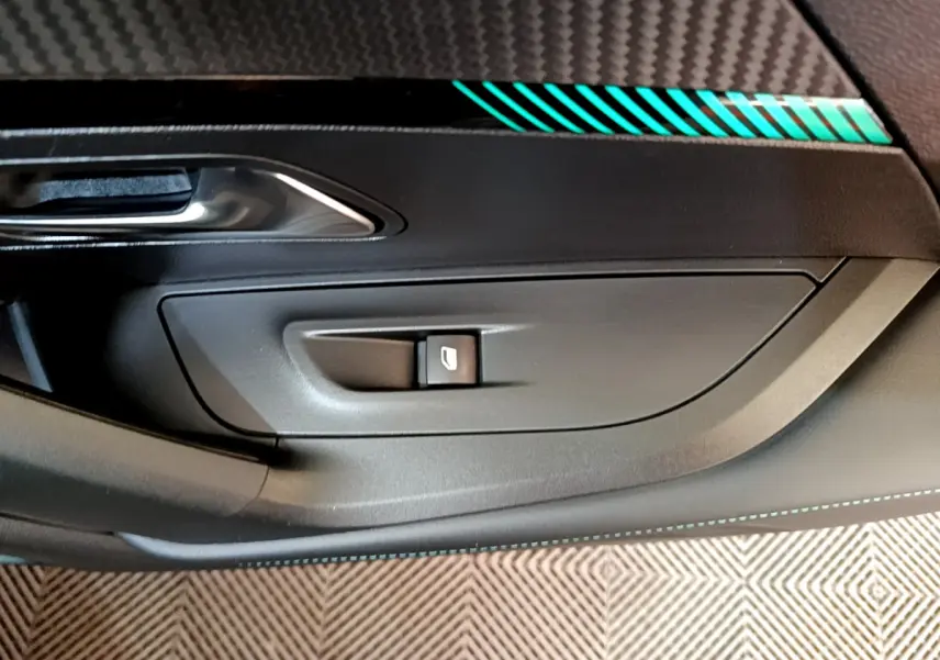 Détail de la commande de lève-vitre côté conducteur avec insert décoratif turquoise sur porte noire du Peugeot 2008 gris foncé.