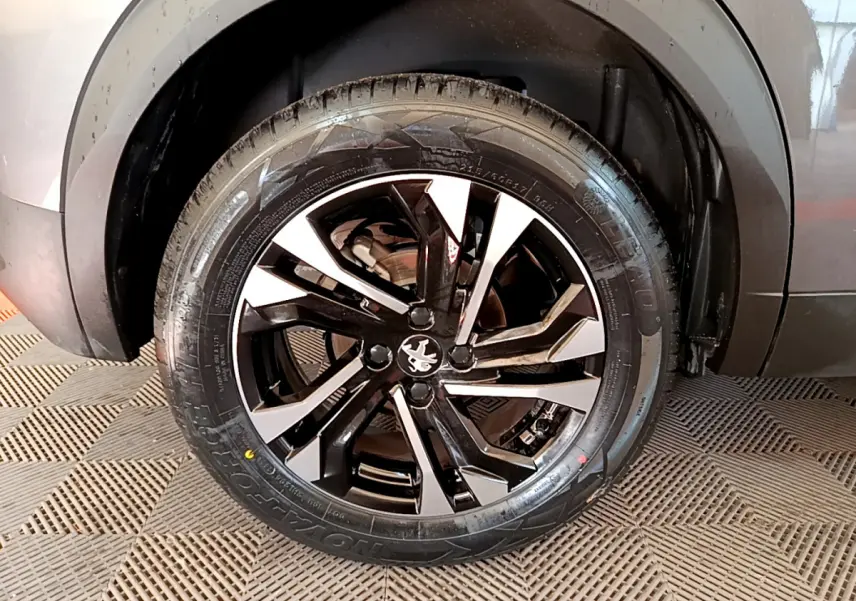 Gros plan sur la roue avant droite du Peugeot 2008 gris foncé avec jante alliage noire et argentée.