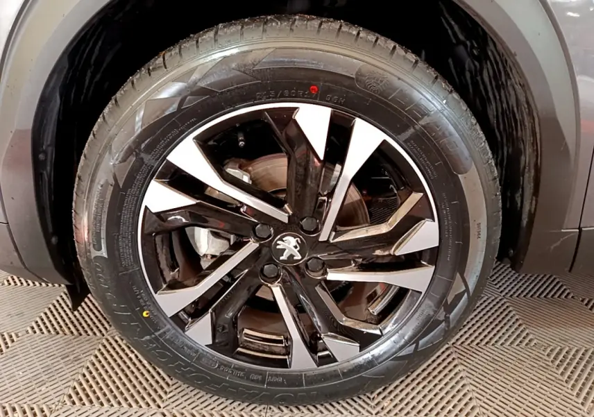 Gros plan sur la roue avant droite du Peugeot 2008 gris foncé avec jante alliage bicolore au design moderne.