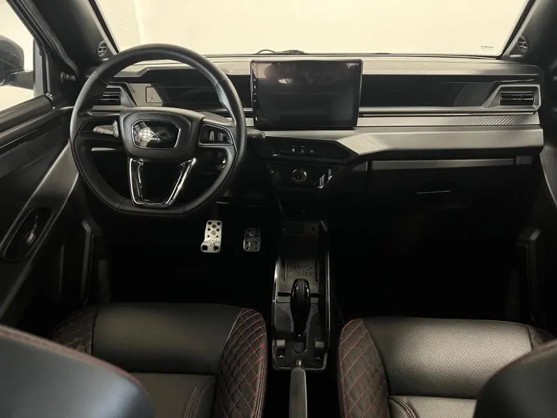 Vue intérieure frontale du tableau de bord gris et noir du Ligier JS50 Sport Ultimate 2025 avec écran tactile et volant multifonction.