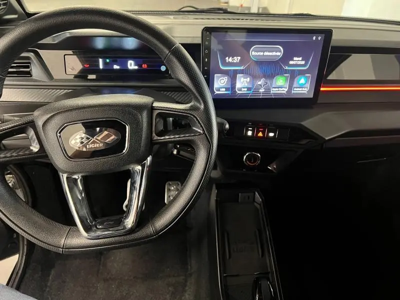 Vue intérieure du tableau de bord et volant noir de la Ligier JS50 Sport Ultimate 2025 avec écran tactile central lumineux.