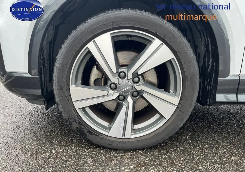 Gros plan sur la jante alu 18 pouces style 5 branches du côté gauche d’un Audi Q2 blanc Ibis.
