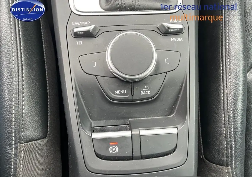 Gros plan sur la console centrale noire en cuir avec commandes multimédia et frein à main électrique de l'Audi Q2.