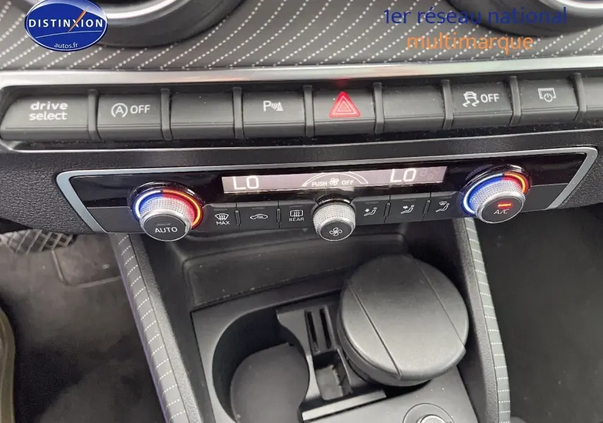 Vue rapprochée de la console centrale de l'Audi Q2, avec commandes climatisation et boutons multifonctions.