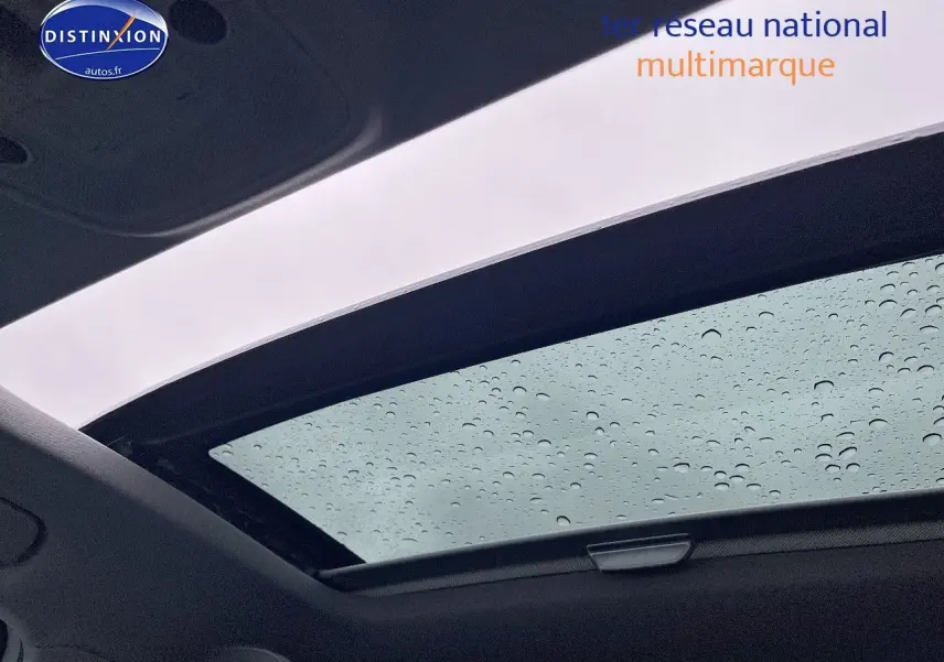 Toit ouvrant électrique panoramique avec gouttes de pluie sur Audi Q2 blanc Ibis, vue intérieure vers le ciel.