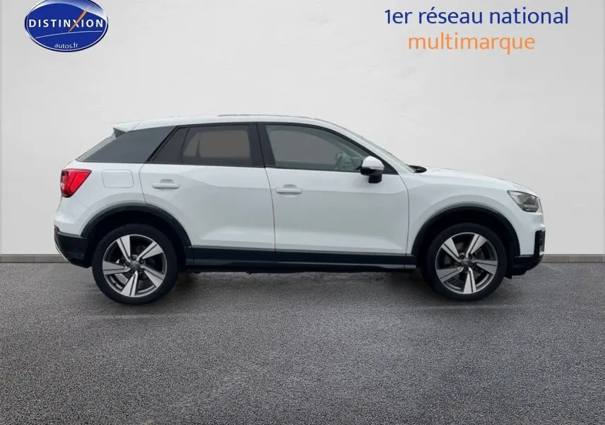 Profil droit d'un Audi Q2 blanc Ibis avec jantes 18 pouces et vitres surteintées sur fond neutre.