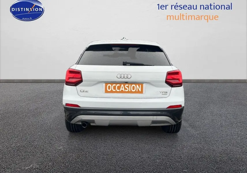 Vue arrière d’un Audi Q2 blanc Ibis avec vitres surteintées et plaque d’immatriculation orange « OCCASION ».