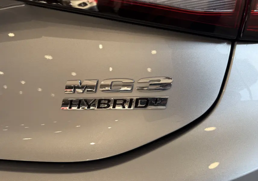 Gros plan sur l’inscription chromée MG3 Hybrid+ sur la carrosserie Cosmic Silver à l’arrière du véhicule.