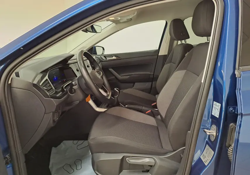 Vue côté gauche de l'intérieur bleu récif d'une Volkswagen Polo 2025, sièges avant gris et volant cuir multifonctions.