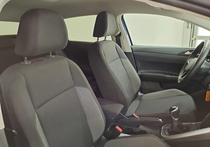 Vue intérieure côté droit de la Volkswagen Polo Bleu Récif 2025, montrant les sièges avant en tissu gris et le levier de vitesses manuel.