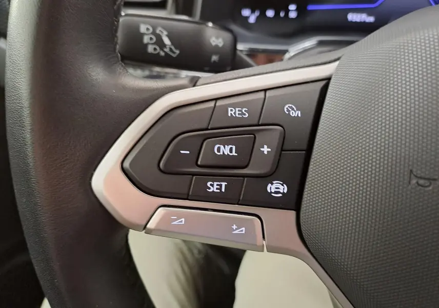 Gros plan sur les commandes du régulateur de vitesse au volant cuir d'une Volkswagen Polo Bleu Récif 2025.