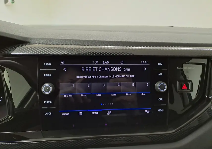 Vue rapprochée de l'écran tactile central noir du tableau de bord d'une Volkswagen Polo 2025, affichant une radio DAB.