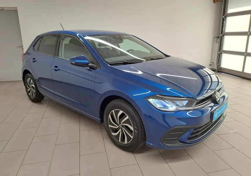 Volkswagen Polo 2025 Bleu Récif vue 3/4 avant droit avec phares LED allumés en intérieur showroom.
