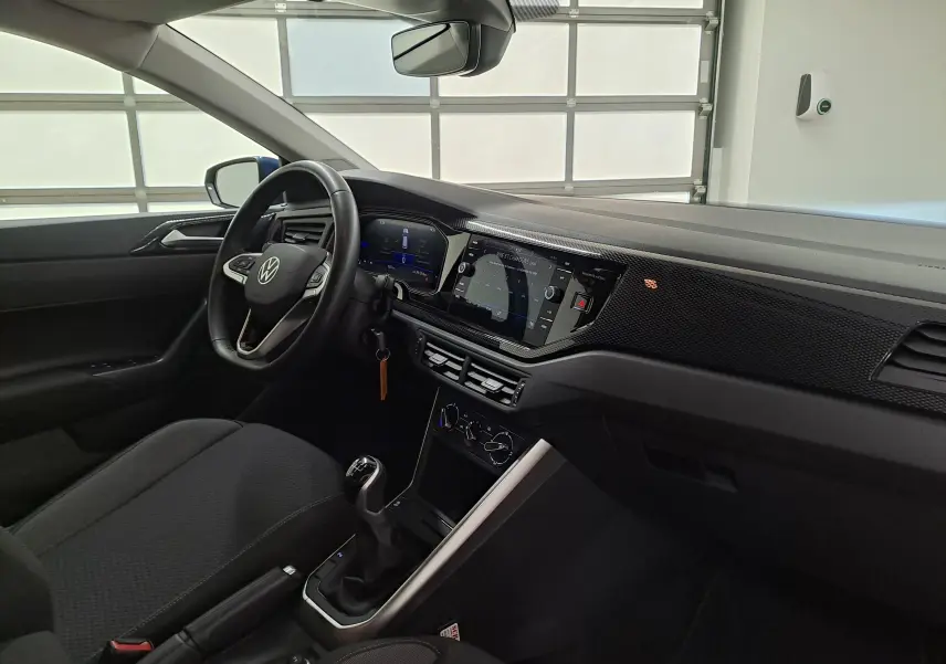 Vue intérieure côté conducteur de la Volkswagen Polo 2025 avec tableau de bord digital et console centrale noire.